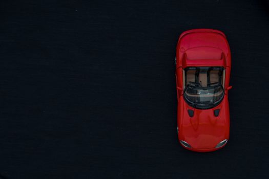 Flat lay of a red toy car with black background