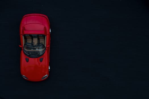 Flat lay of a red toy car with black background