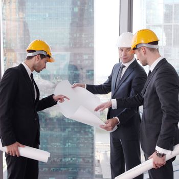 Businessmen and architect team in office planning construction project with office buildings