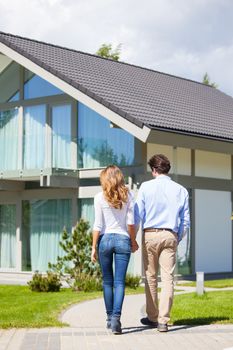 Happy couple walking outdoors near their house