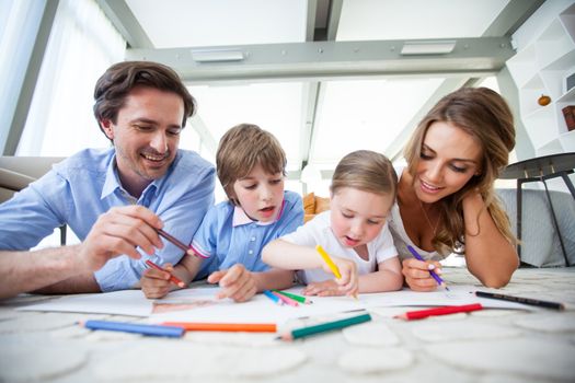 Charming family with children drawing together on the floor in a living room