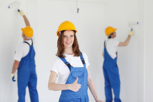Two young workers in uniform painting the wall