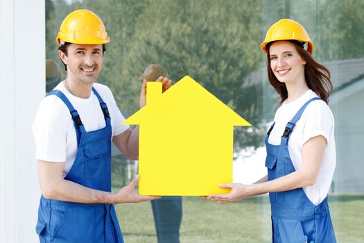 Construction workers showing house model symbol and friendly smiling