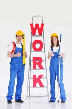 Happy couple in uniform holding tools and ladder with work letters