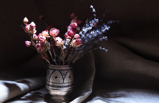 Vintage still life with bouquet of dried flowers in a silver vase