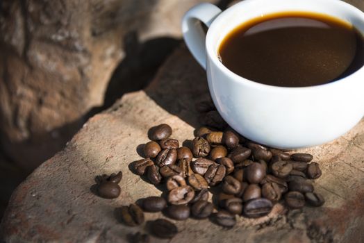 Cup of coffee and coffee beans on a stone background.