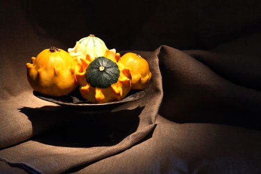 Vintage still life with few small pumpkins in old metal bowl