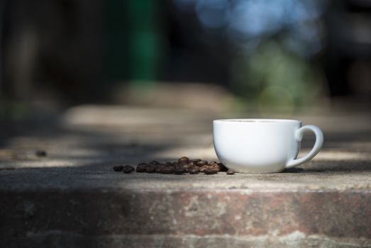 Cup of coffee and coffee beans on a stone background.