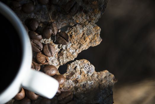 Cup of coffee and coffee beans closeup on iron rusty background.