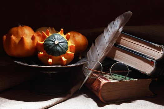 Vintage still life with few small pumpkins in a metal vase near old book