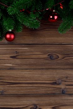 Christmas decoration on wooden background, fir tree branch, red baubles