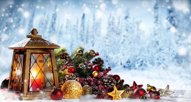 Burning candles , lantern and christmas decoration on winter forest bokeh background
