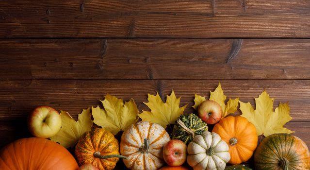 Many colorful pumpkins and maple leaves frame on wooden background , autumn harvest , Halloween or Thanksgiving concept