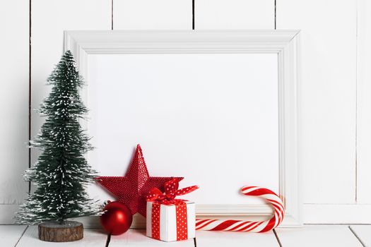 Decorative Christmas tree candy cane , star , baubles and gift box and blank paper fith frame on white wooden background