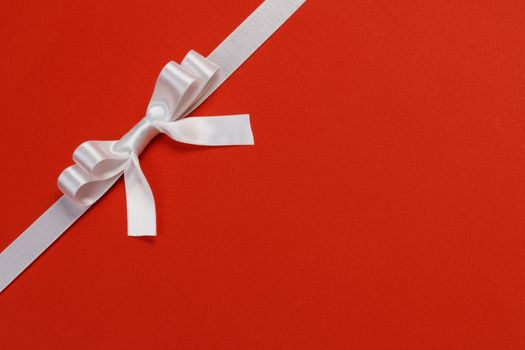 White gift bow on red background holiday gift concept