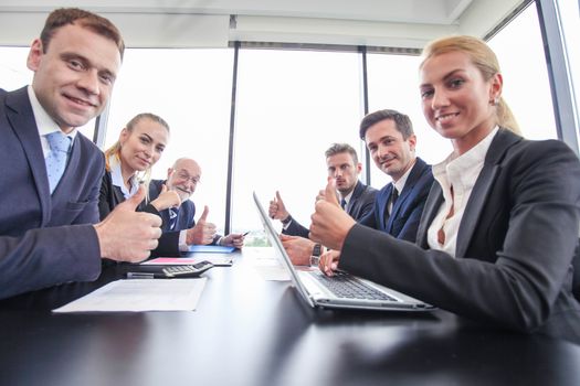 Happy business team having a meeting at office table, showing OK with thumbs up