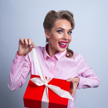 Happy beautiful funny woman unpacks holiday gift in red box