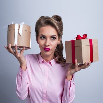 Young woman guessing compare gifts puting her ear to the presents with bows