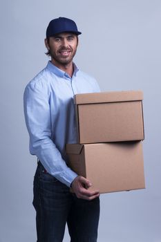 Delivery man carrying cardboard box on gray background