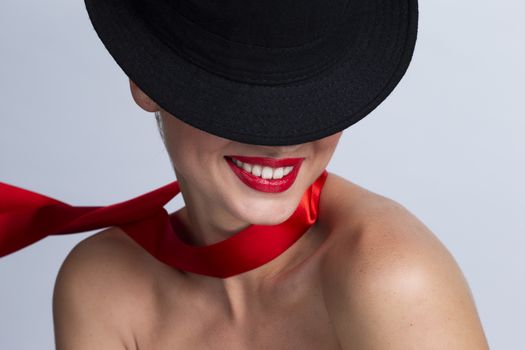 Portrait of beautiful woman in black hat with red ribbon on neck