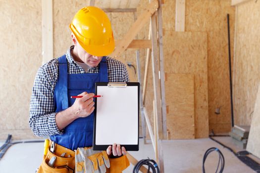 Portrait of foreman pointing at white folder plate standing at construction site