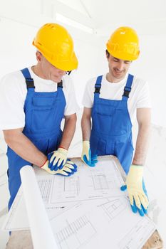Building, construction, development, teamwork and people concept - close up of builders in hardhats working with blueprint