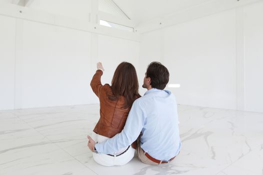 Couple at their new empty apartment pointing at space and planning future