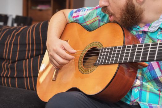 Young man musician playing acoustic guitar