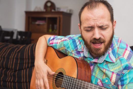 Young man musician playing acoustic guitar