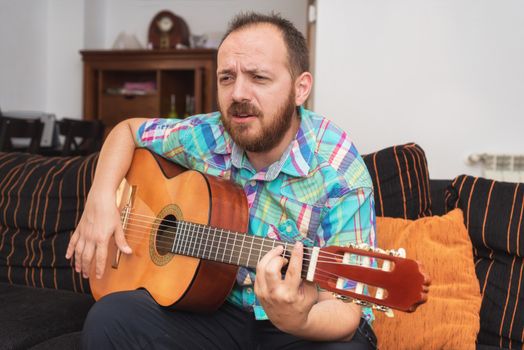 Young man musician playing acoustic guitar