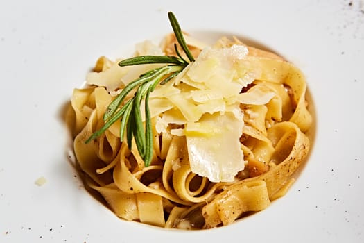Close-up italian pasta plate with grated parmesan cheese and basil leaf.