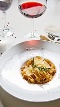 Close-up italian pasta plate with grated parmesan cheese and basil leaf.