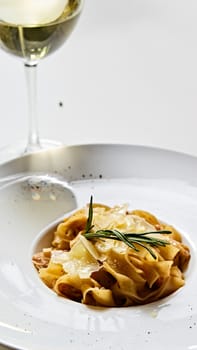 Close-up italian pasta plate with grated parmesan cheese and basil leaf.