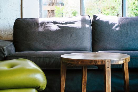 Stylish interior of living room with small design table and gray sofa.