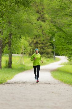 Sporty young female runner in city park. Running woman. Female runner during outdoor workout in nature. Fitness model outdoors. Weight Loss. Healthy lifestyle.