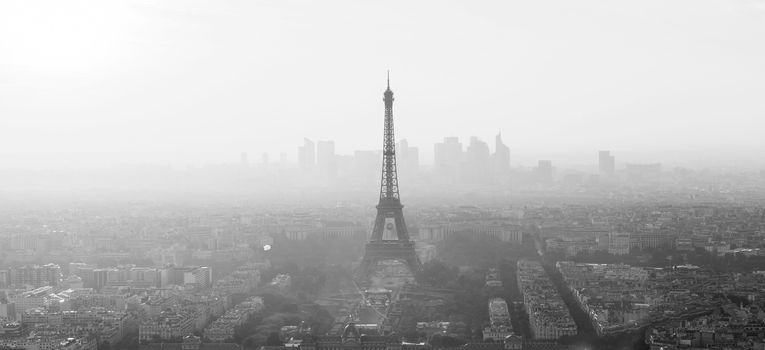 Aerial view of Paris with Eiffel tower and major business district of La Defence in background at sunset. Black and white image.