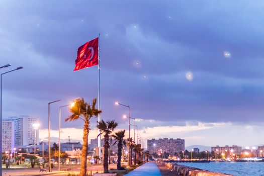 a good looking soft colored nightscape shoot of mavisehir coast - there is turkish flag and good looking city under clouds. photo has taken from izmir/turkey.