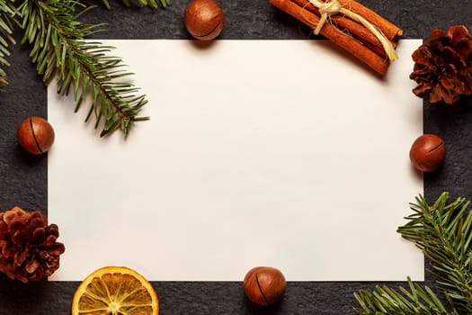 Christmas composition, blank for greeting card or other design - old paper with a Christmas tree branch and decorations on a dark background, flat lay, top view, copy space, place for text.