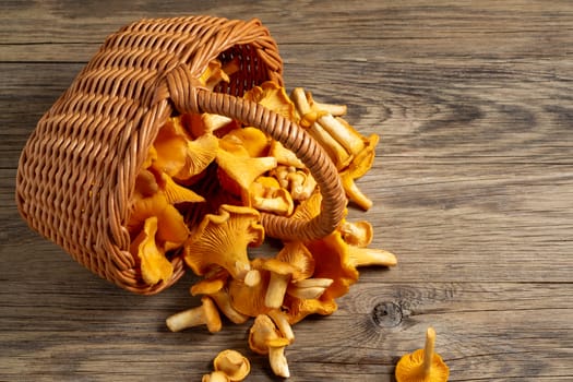 Wicker basket with chanterelles over an old wooden table.