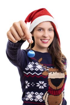 Close up shot of a beautiful smiling girl in a festive sweater with a Santa`s hat on, holding a Christmas decoration, isolated on a white background.