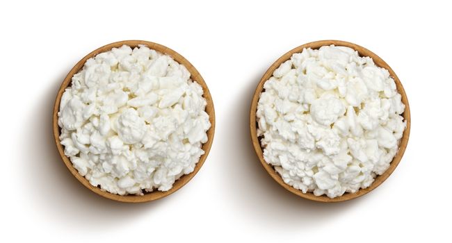 Cottage cheese in wooden bowl isolated on white background with clipping path. Top view