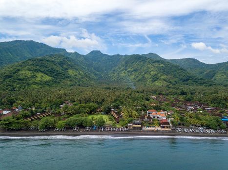 Aerial view of Amed beach in Bali, Indonesia. Traditional fishing boats called jukung on the black sand beach.