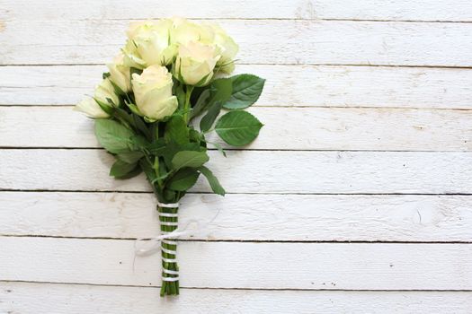 The picture shows white roses on wooden boards.