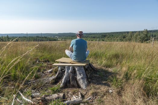 man sitting relax on a tree and yoga in the forest of the belgium nature park of the ardennes