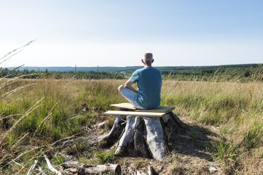 man sitting relax on a tree and yoga in the forest of the belgium nature park of the ardennes