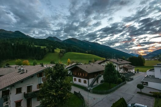 Cloudy sky, green hills, Tyrolean lodges, high view
