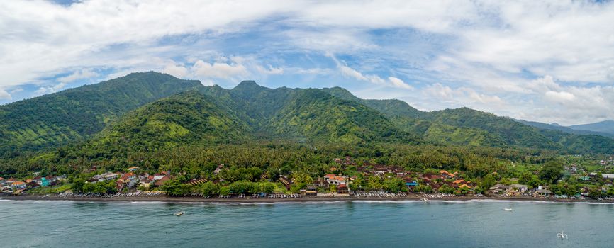 Panoramic aerial view of Amed beach in Bali, Indonesia. Traditional fishing boats called jukung on the black sand beach.