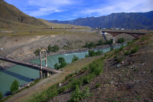 Old and new bridge over the bed of a mountain river of turquoise color. Altai, Siberia, Russia.