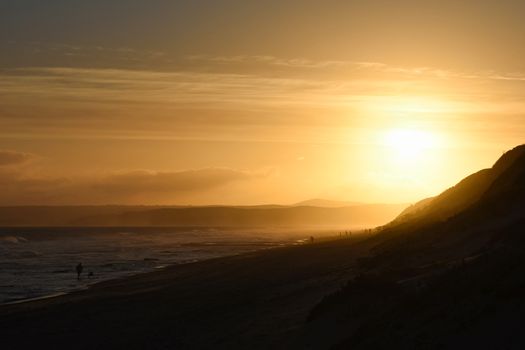 Last light fading from the beach as the bright sun sets in the distance, Mossel Bay, South Africa