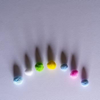 some felt balls  of various colors on a white surface